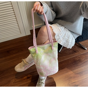 Detailed close-up of a floral canvas tote bag with pink straps in a lifestyle setting