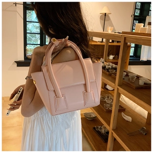 Close-up of light pink PU leather handbag with matte finish in a warm cafe setting