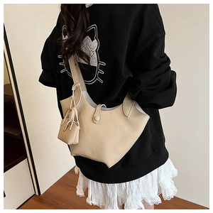 Detail of beige bucket bag with lychee grain leather texture and mini pendant pouch