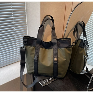 Detail of military green nylon tote bag featuring adjustable straps and buckle closures