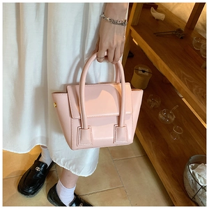 Detail of a soft pink PU leather handbag with gold rivets and elegant top handles