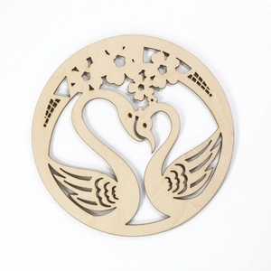 Round wooden coaster with laser-cut swan heart and floral patterns on white background