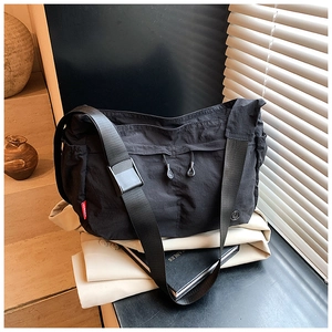 Detail of black nylon crossbody bag with zipper pocket and red brand label on fabric