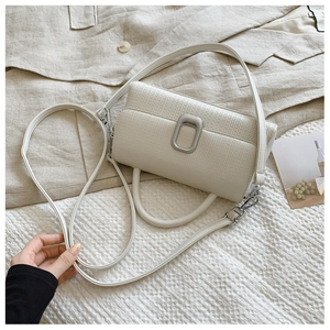Macro shot of beige pebble leather handbag showing silver metal buckle and refined texture