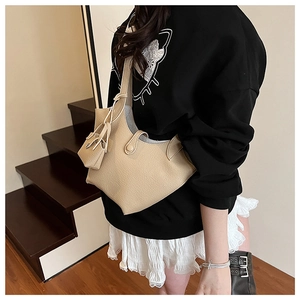 Detail of minimalist beige bucket bag with matching mini pouch and pebbled leather texture