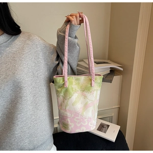 Detail of canvas bucket bag featuring floral tie-dye pattern and pink handles