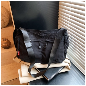 Macro detail of black nylon crossbody bag featuring drawstring design and side brand label