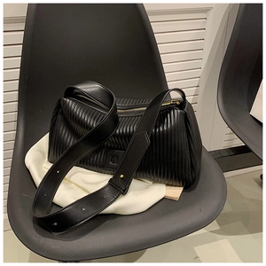 Close-up of black pleated texture bag with golden zipper and wide flat shoulder strap
