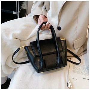 Detail of a chic black PU leather handbag featuring elegant gold hardware and a top handle