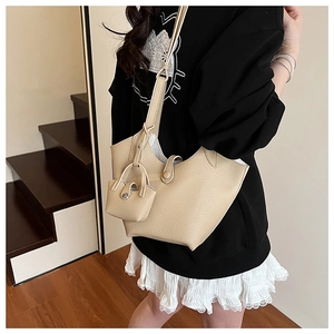 Detail of a creamy beige bucket bag with lychee grain texture and a mini matching pouch