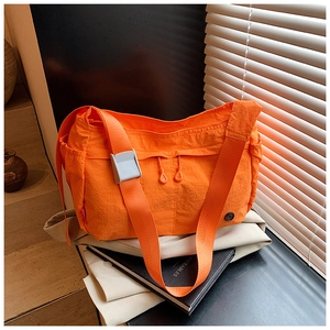 Detail of orange waterproof nylon crossbody bag with wide strap and side pockets
