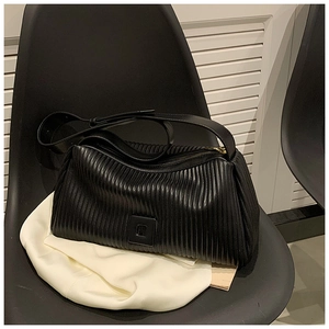 Close-up of black plissé pleated shoulder bag with square patch and gold zipper details