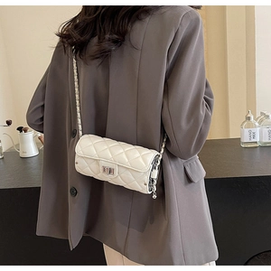 Detail of creamy white quilted cylinder bag with silver metal chain and twist-lock