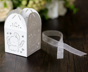 Detail of laser-cut white favor box with cute elephant patterns and organza ribbon