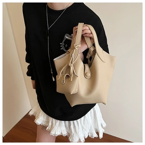 Close-up of beige lychee texture bucket bag with matching small pouch on a model