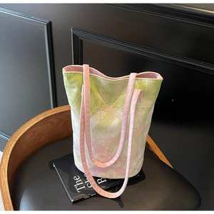 Detail of pink and green floral canvas tote bag with thin handles on a leather chair