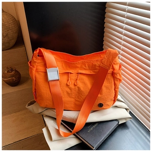 Close-up of orange nylon crossbody bag with dual drawstring zippers and wide shoulder strap