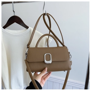 Detail of a brown vintage textured mini square bag with silver metal clasp and handle