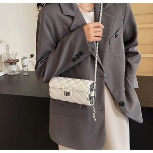 White quilted barrel crossbody bag with silver chain strap shown in lifestyle setting