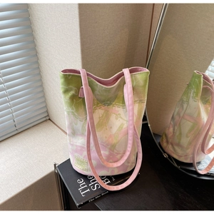 Detail of floral canvas bucket bag with pink straps and logo tag in lifestyle setting