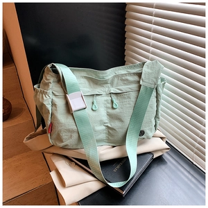 Detail of mint green nylon messenger bag showing drawstring and side pocket texture