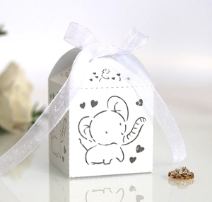 Detail of white hollow-out candy box with elephant pattern and white organza ribbon