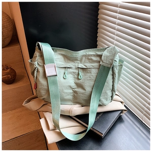Close-up of mint green nylon crossbody bag with side drawstring and adjustable strap