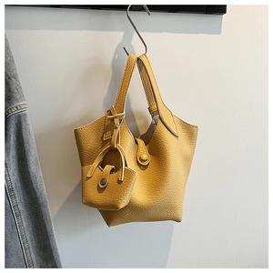 Detail of yellow lychee leather bucket bag featuring a mini matching coin purse attachment