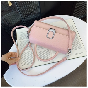 Detail of pink lychee leather cylinder bag with silver hardware on a book