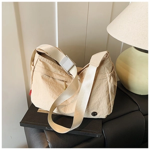 Close-up of beige nylon crossbody bag with wide strap and metallic logo detail