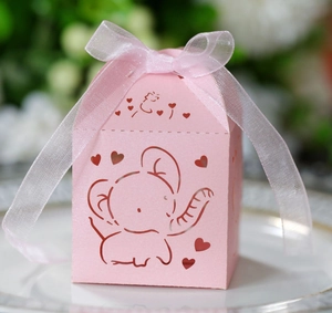 Close-up of pink laser-cut elephant candy box with white ribbon on a ceramic plate