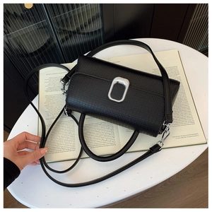 Detailed shot of black lychee grain leather handbag with silver metallic buckle on a magazine