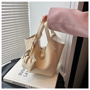 Detail of cream bucket bag with lychee texture and matching mini pouch accessory