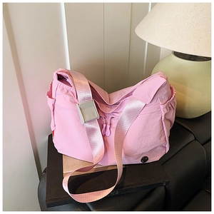 Detail of pink nylon hobo bag featuring drawstring zipper and side pockets on a bench