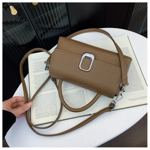 Detail of brown litchi pattern leather handbag with silver U-shaped metal lock and strap
