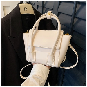 Detail of minimalist beige PU leather handbag with gold hardware and flap closure