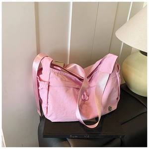 Detail view of pink nylon crossbody bag showing wide strap, side pocket and zipper closure