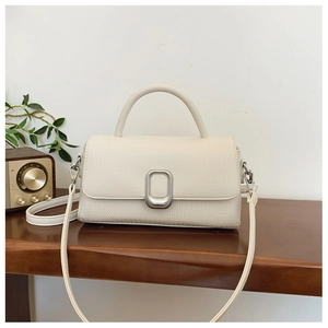 Detail of off-white woven texture handbag with silver metal lock on a wooden table