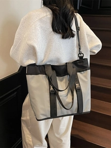 Large color-block tote bag in grey and black nylon fabric shown on a crossbody model