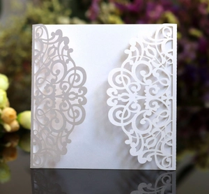 Macro detail of white laser-cut lace wedding invitation cover with pearl texture finish