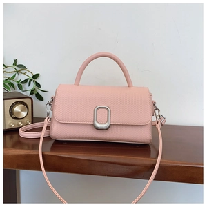 Close-up of pink lychee leather handbag with silver metal buckle on a wooden table