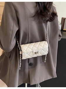 White quilted barrel crossbody bag with chain strap shown on model in natural indoor light