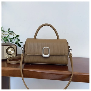 Detail of woven embossed texture on brown PU leather handbag with silver metal buckle