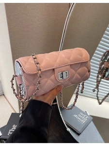 Pink quilted cylindrical chain bag with silver lock and leather strap held by hand