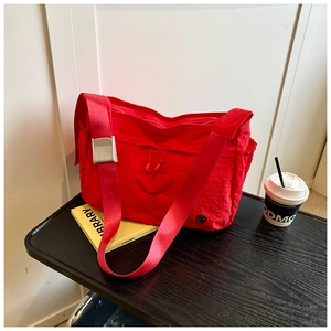 Close-up of a red nylon crossbody bag with functional pleated texture and metal buckle