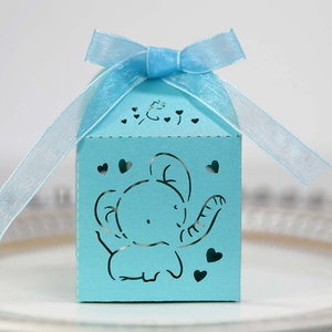 Detail of light blue laser-cut gift box with elephant pattern and ribbon on white plate