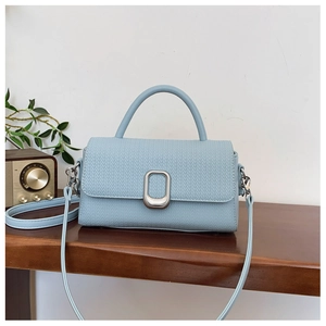 Detail of light blue woven texture handbag with silver buckle on wooden table