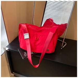 Macro detail of red nylon dumpling bag showing crinkled texture and adjustable wide strap