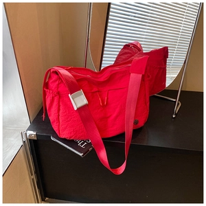 Close-up of red wrinkled nylon crossbody bag featuring drawstring detail and side pocket