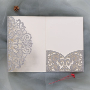 Macro detail of laser cut silver glitter wedding invitation sleeve with floral patterns